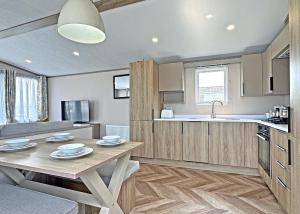 a kitchen and dining room with a table in a room at Golden Anchor Caravan Park in Chapel Saint Leonards