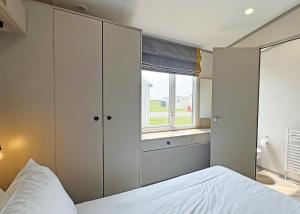 a bedroom with a bed and a window at Golden Anchor Caravan Park in Chapel Saint Leonards