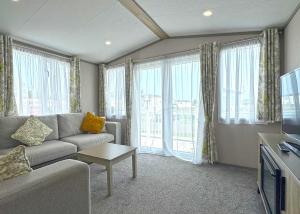 a living room with a couch and a tv at Golden Anchor Caravan Park in Chapel Saint Leonards +31 photos