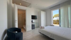 a bedroom with a bed and a window and a chair at Sunset Bay in Torre Suda