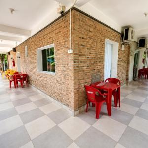 a brick wall with red tables and red chairs at Pousada Rancho Texas Ubatuba in Ubatuba