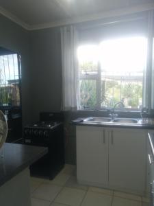 a kitchen with a sink and a stove and a window at Radiant Residence in Grahamstown