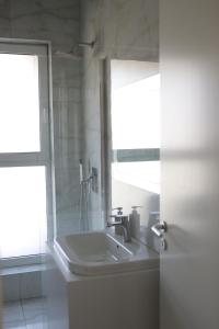 a white bathroom with a sink and a window at Boulevard View in Tirana