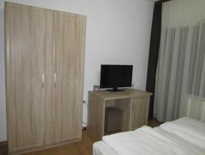 a bedroom with a bed and a television on a cabinet at ,, La Moara '' in Peştişani