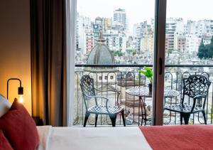 a room with a bed and a balcony with a table and chairs at Reco by DOT Suites in Buenos Aires