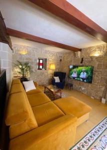 a living room with a large couch and a tv at Kercem Boutique Farmhouse in Kerċem