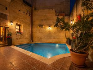 a swimming pool in a building with a potted plant at Kercem Boutique Farmhouse in Kerċem
