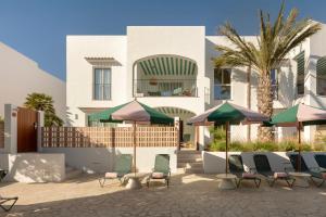 a patio with chairs and umbrellas in front of a building at Inturotel Esmeralda Villas in Cala d´Or