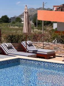 a swimming pool with two lounge chairs and an umbrella at Lux Hotel M - Boutique Hotel & Restaurant in Dobra Voda