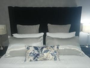 a bed with white pillows and a black headboard at Radiant Residence in Grahamstown