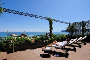 a woman laying on a beach chair at a resort at Hotel Ligure in Alassio