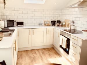 a white kitchen with white cabinets and appliances at Derbyshire House Apartment 3 - Cavendish in Buxton