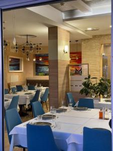 a dining room with white tables and blue chairs at Lux Hotel M - Boutique Hotel & Restaurant in Dobra Voda