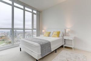 a white bedroom with a large white bed and windows at Lakeview 1 Bed 1 Den by Rogers Centre in Toronto