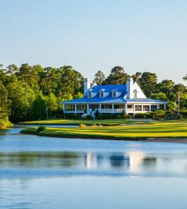 a large house with a blue roof next to a lake at Litchfield Beach & Golf Resort in Pawleys Island