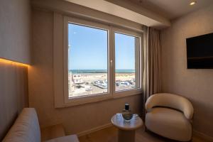 a living room with a view of the beach from a window at The CORNR Seaview in Nieuwpoort