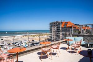 a patio with tables and chairs and a view of the beach at The CORNR Seaview in Nieuwpoort