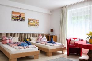 a living room with two beds and a red chair at Hotel Garni in Burghausen