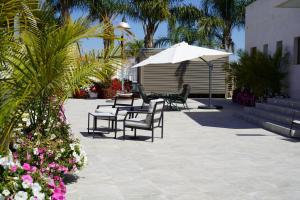 a patio with chairs and an umbrella and flowers at אחוזת החושן - וילה מהממת עם בריכה פרטית in Tirosh