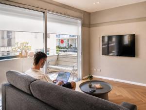 a man sitting on a couch using a laptop at Florentin House with MAMAK - By HOMY in Tel Aviv