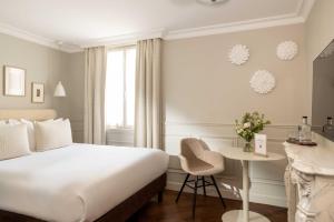 a hotel room with a bed and a desk at Hôtel Madeleine Haussmann in Paris