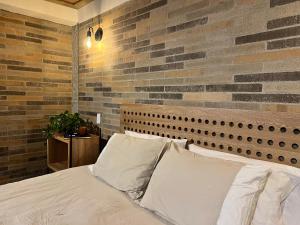 a bedroom with a brick wall and a bed with pillows at Autenthico Sajonia Hotel Aeropuerto in Rionegro