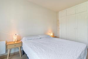 a white bedroom with a bed and a night stand at Bellavista Los Pinos in Almuñécar
