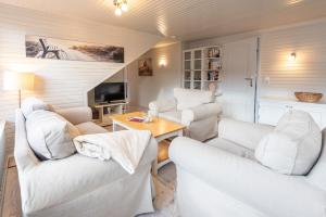 a living room with two white couches and a table at Haus Strandkind in Sylt