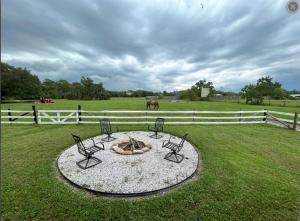 a fire pit in a field with two chairs and a fence at The bunkhouse in Sarasota +6 photos