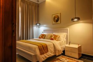 a bedroom with a bed with white sheets and pillows at Ruts Golden Homes in Kampala