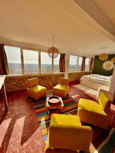 a bedroom with yellow chairs and a bed and windows at Chez les copains in Sidi Kaouki