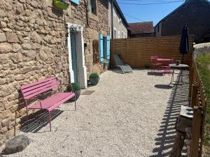 a pink bench sitting next to a stone building at La Petite Maison - 4 voyageurs in Voudenay-lʼEglise
