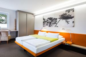 a bedroom with a bed with an orange headboard at Hotel Windschur in Sankt Peter-Ording