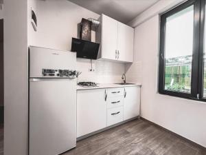 a white kitchen with a refrigerator and a window at David Palace Hotel Ureki in Ureki