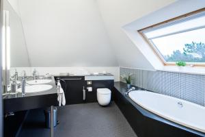 a bathroom with a tub and a toilet and a window at Hotel Windschur in Sankt Peter-Ording
