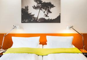 a bedroom with a bed with two lamps at Hotel Windschur in Sankt Peter-Ording +21 photos