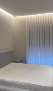 a white bedroom with a bed and a window at Aura Stay Apartment in Tirana