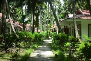a path in front of a house with palm trees at Cross Bill Beach Resort in Havelock Island