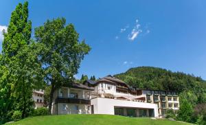 budynek na szczycie wzgórza z drzewami w obiekcie Seehotel Billroth w mieście St. Gilgen