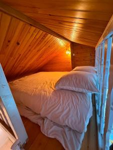 a bed in a room with a wooden ceiling at La Cabane du Pti' Bonheur in Saint-Coulomb