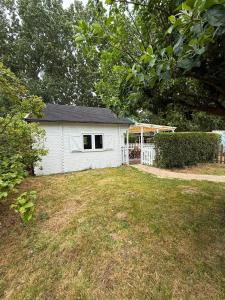 a small white house in a yard with a fence at La Cabane du Pti' Bonheur in Saint-Coulomb
