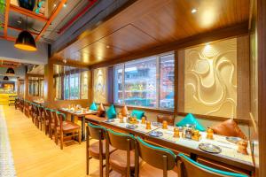 a restaurant with long tables and chairs and a window at Treebo Premium Merrit in Katrab