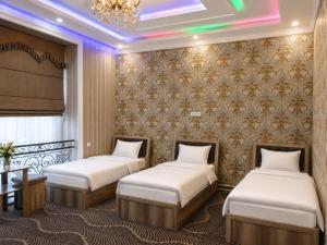 two beds in a room with a wall at Zamin Hotel in Shahrisabz +8 photos