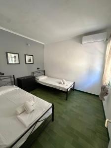two beds in a room with green floors at Olive terra holiday aparments in Lefkimmi