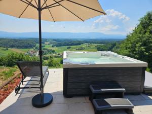 a hot tub with a chair and an umbrella at Pirman Vineyard Cottage in Bučka