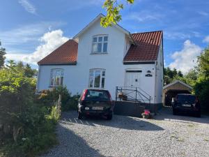 a white house with a car parked in the driveway at Friisenborg in Jelling +2 photos