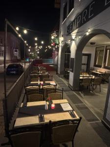 a row of tables and chairs on a patio at night at Sempre Bello in Iffezheim