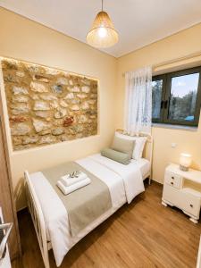 a bedroom with a bed and a stone wall at Olive Coast House 3 100m from the sea in Kyparissia