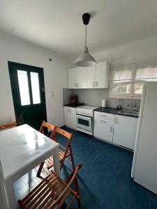 a kitchen with white cabinets and a table and chairs at Olive terra holiday aparments in Lefkimmi