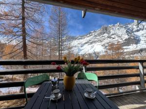 a table with a vase of flowers on a balcony with mountains at Cervinia Mountain View Apartments in Breuil-Cervinia